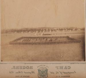Sepia-toned image of a photograph showing people lined up in a rectangular shape. There are people in the middle of the rectangle. Some are on horseback. In the background are trees. 