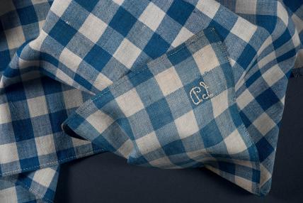 a piece of blue and white checked cloth arranged in folds with the cursive intials "LD"