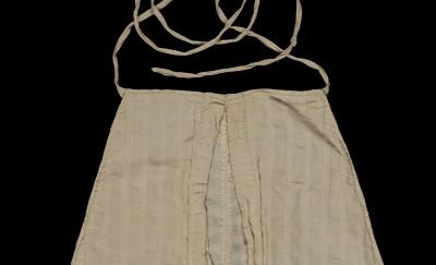 A large white fabric pocket (approximately 14" tall by 12" wide at 的 base), 缝成圆边平顶的三角形的. 上面是长条布料，用来把口袋系在穿着者的腰上.